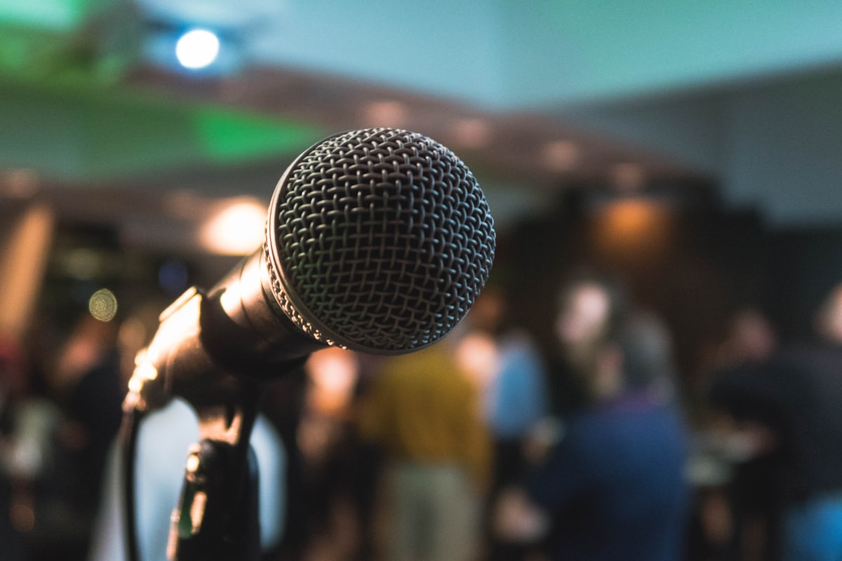 A microphone in focus in front of a gathered room