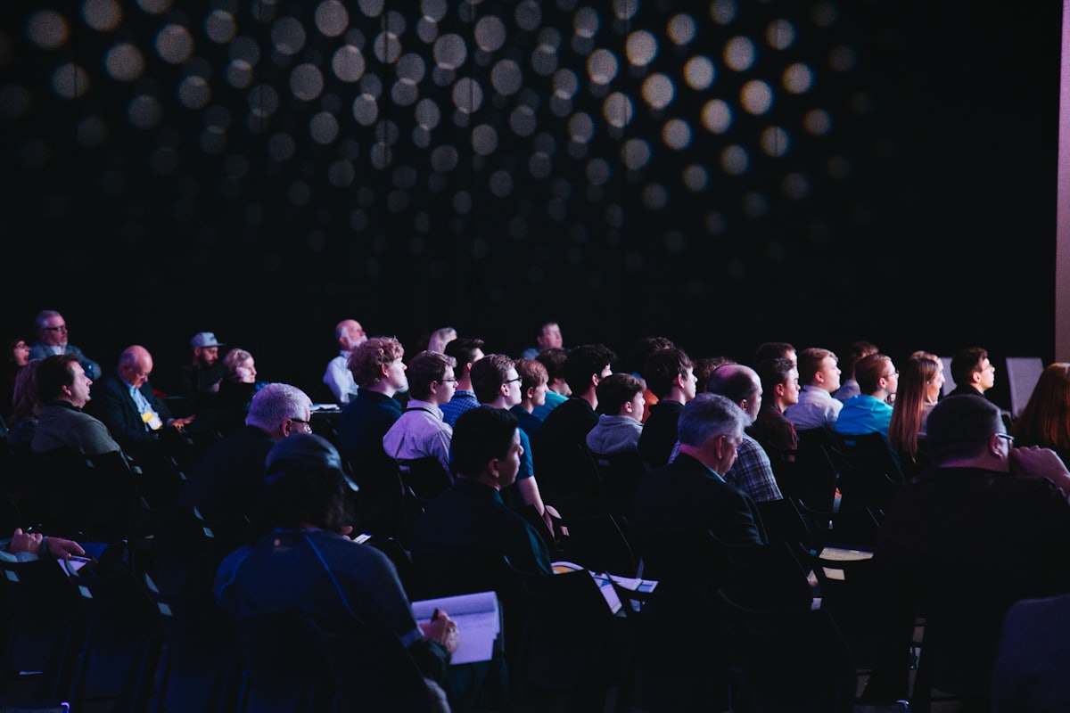 An audience listening closely in a darkened hall